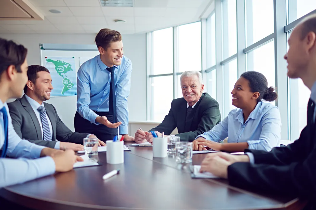 Employee standing with peers and boss at table
