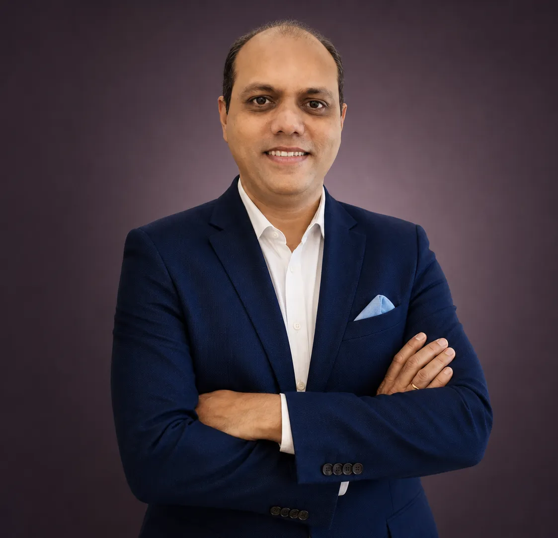 Sanjay K Shetty, energy healing and space-clearing advisor, in a navy blazer with arms crossed.