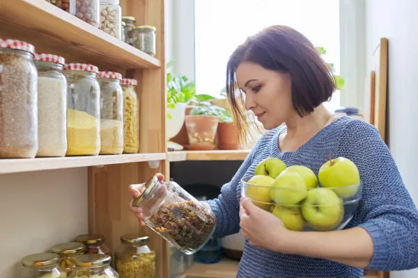 Woman looking at a jar in her kitchen pantry.