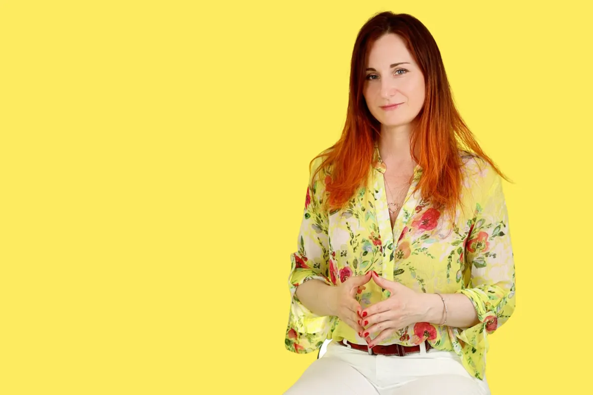 A woman in floral top against bright yellow background