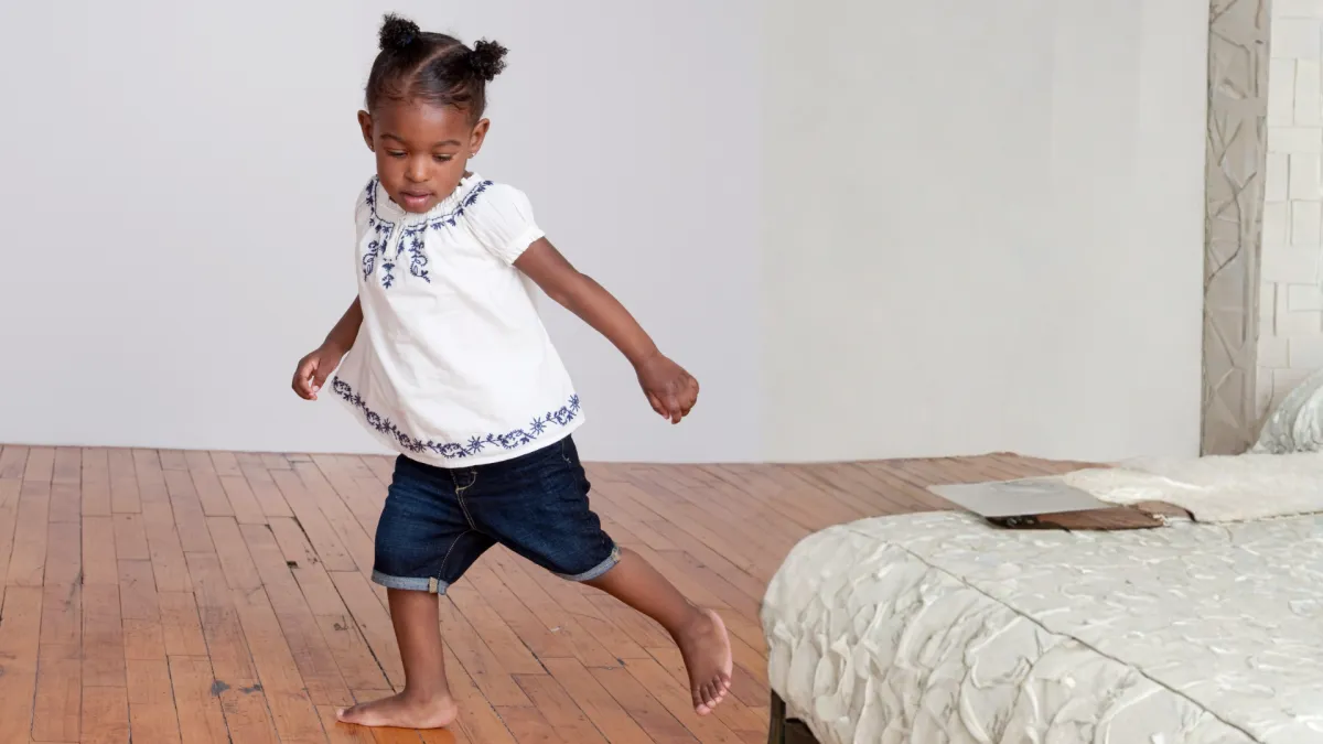 Girl stretches to the side while watching teacher on large screen TV