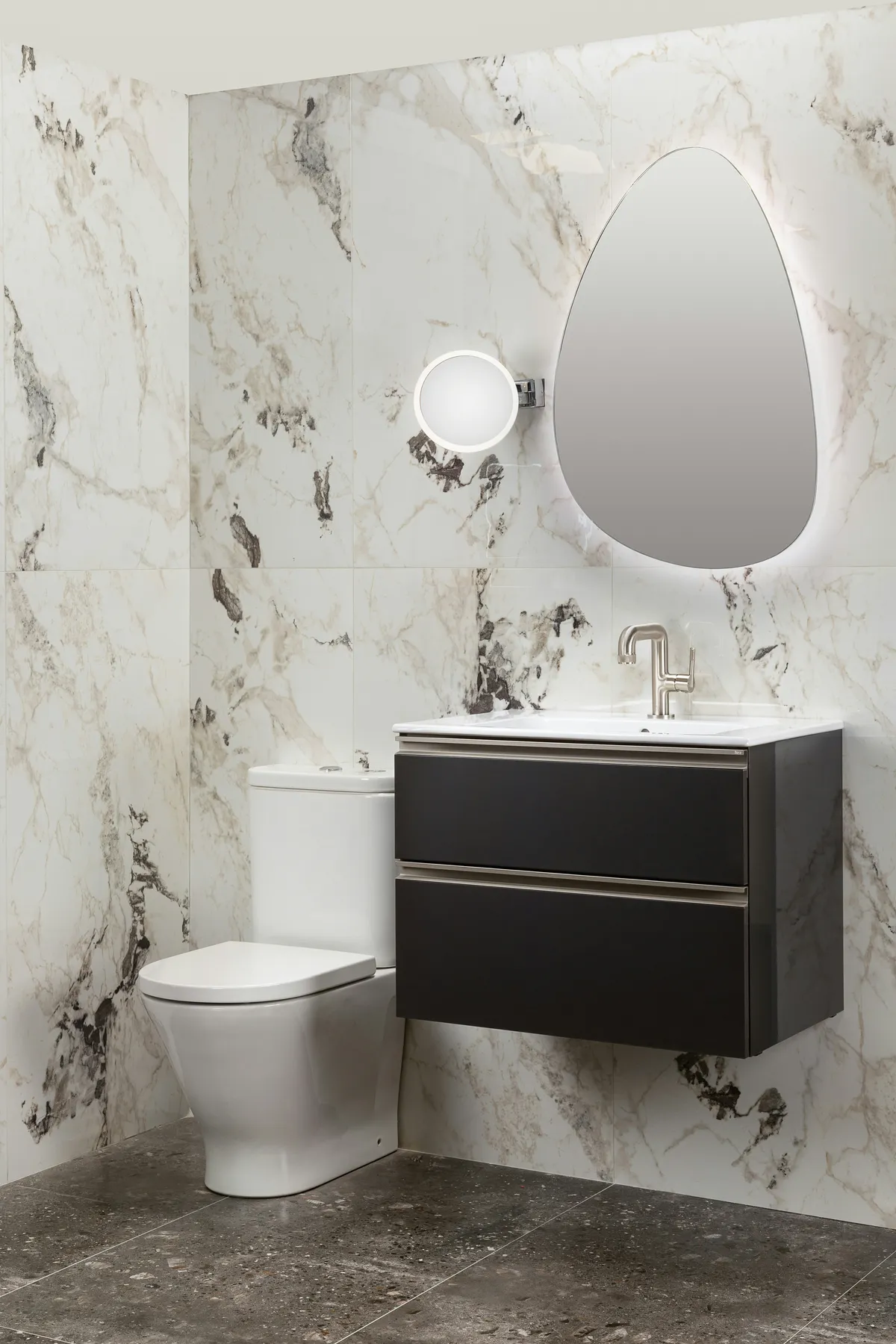 marble tiled bathroom with modern floating sink and round mirror