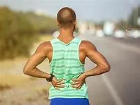 A man holding his lower back in pain, possibly due to muscle strain or injury.