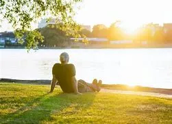 Peaceful person sitting by the lake, representing relaxation and mindfulness through hypnosis therapy sessions.