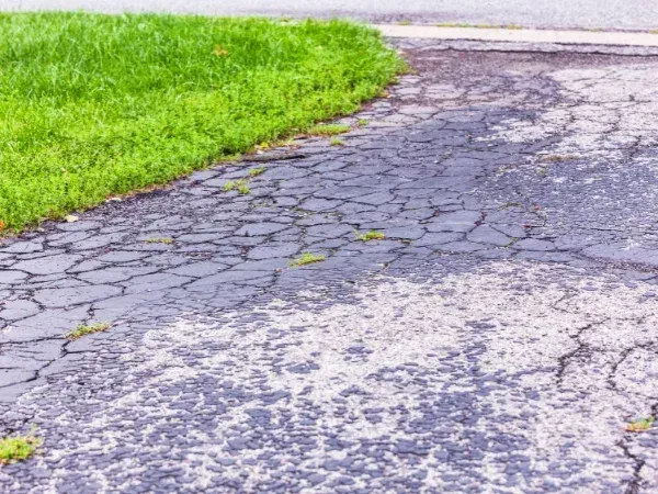 Cracked driveway with heavy dirt and stains before professional pressure washing