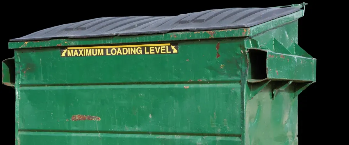 Green commercial dumpster with maximum loading level warning label and closed lid.
