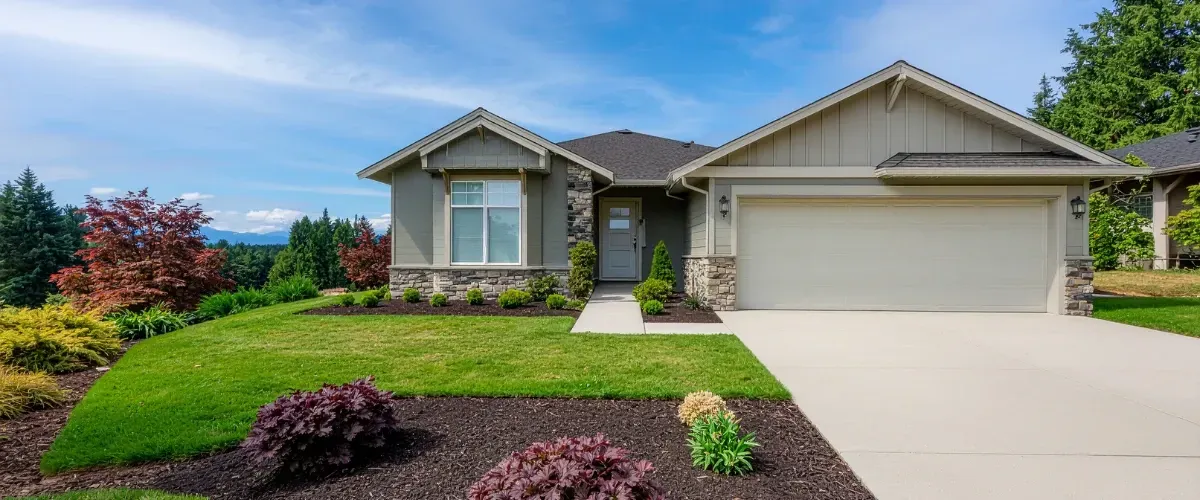 Modern suburban house with landscaped front yard, green lawn, and clear blue sky.