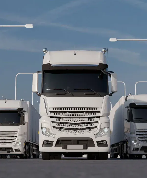 Three modern white semi trucks with trailers parked on an asphalt road under a clear blue sky.