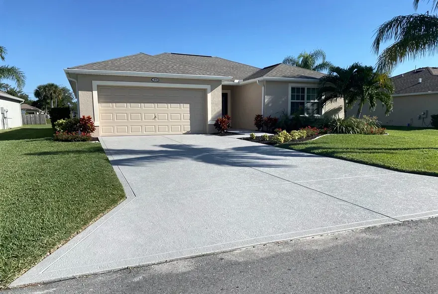 Freshly finished concrete driveway leading to an attached garage at a Lake Worth, Florida home.