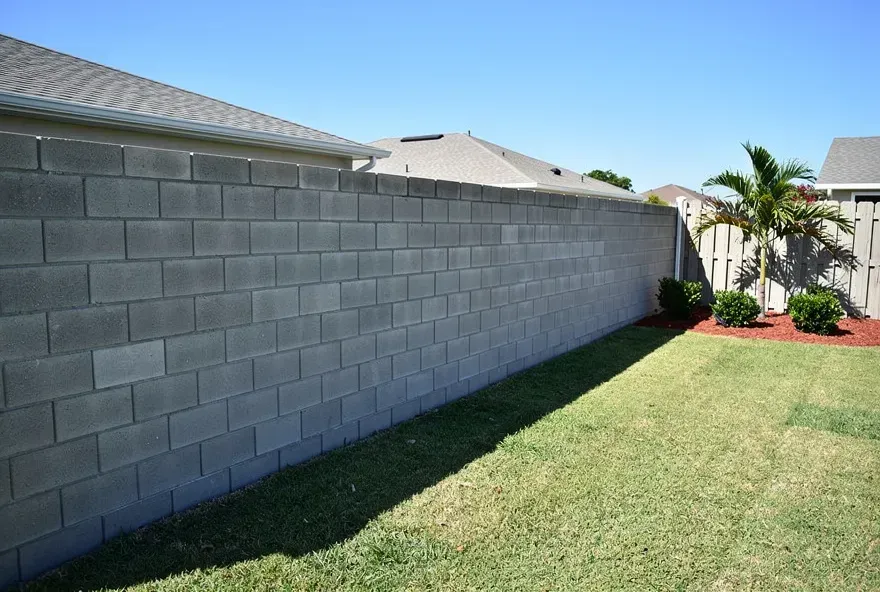 Newly built concrete block wall along a backyard property line in Lake Worth, Florida on a sunny day.