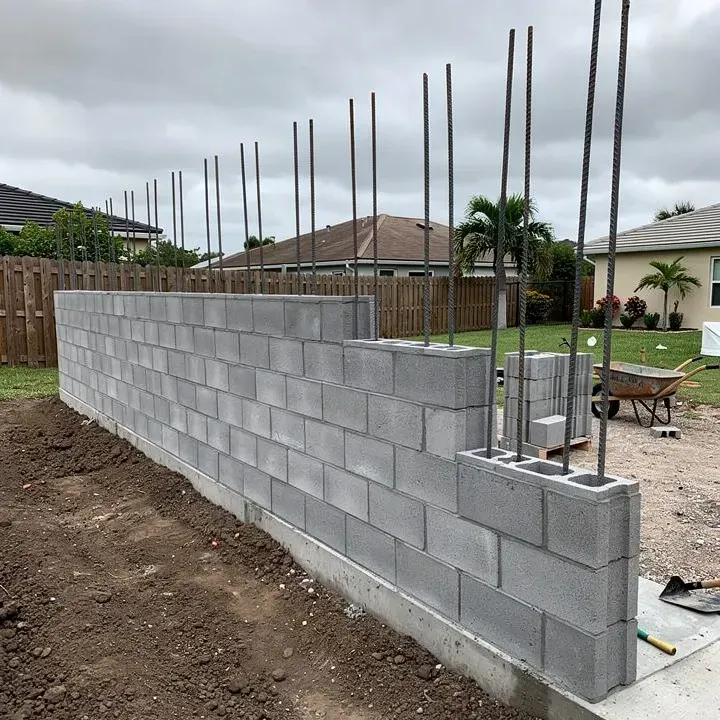 Concrete block wall construction in progress showing CMU blocks with visible rebar cores at residential site in Lake Worth Florida