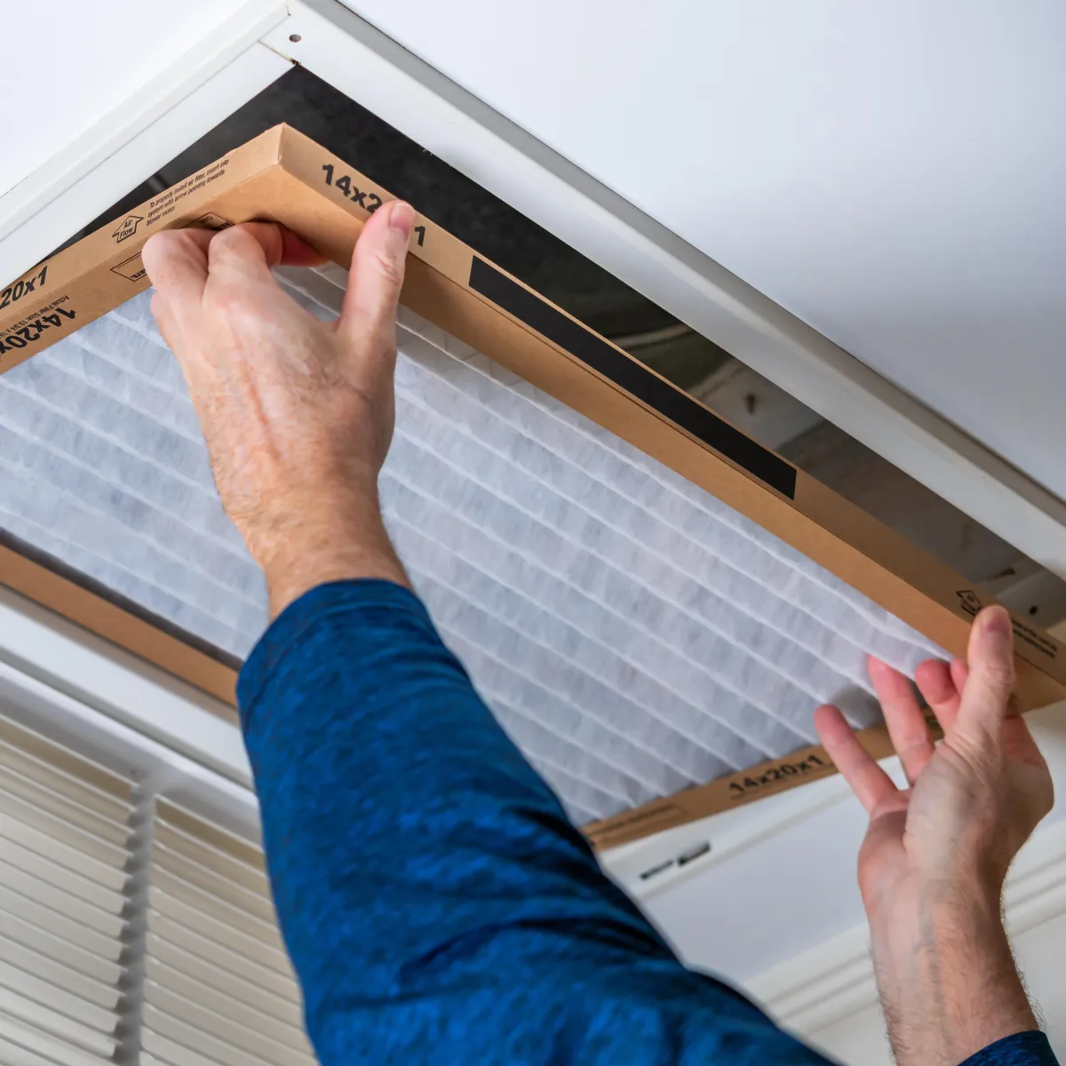 Technician installing a new AC filter in a ceiling vent. Soligo Air’s Central Florida Air Filter Replacement ensures reminders and reliable service