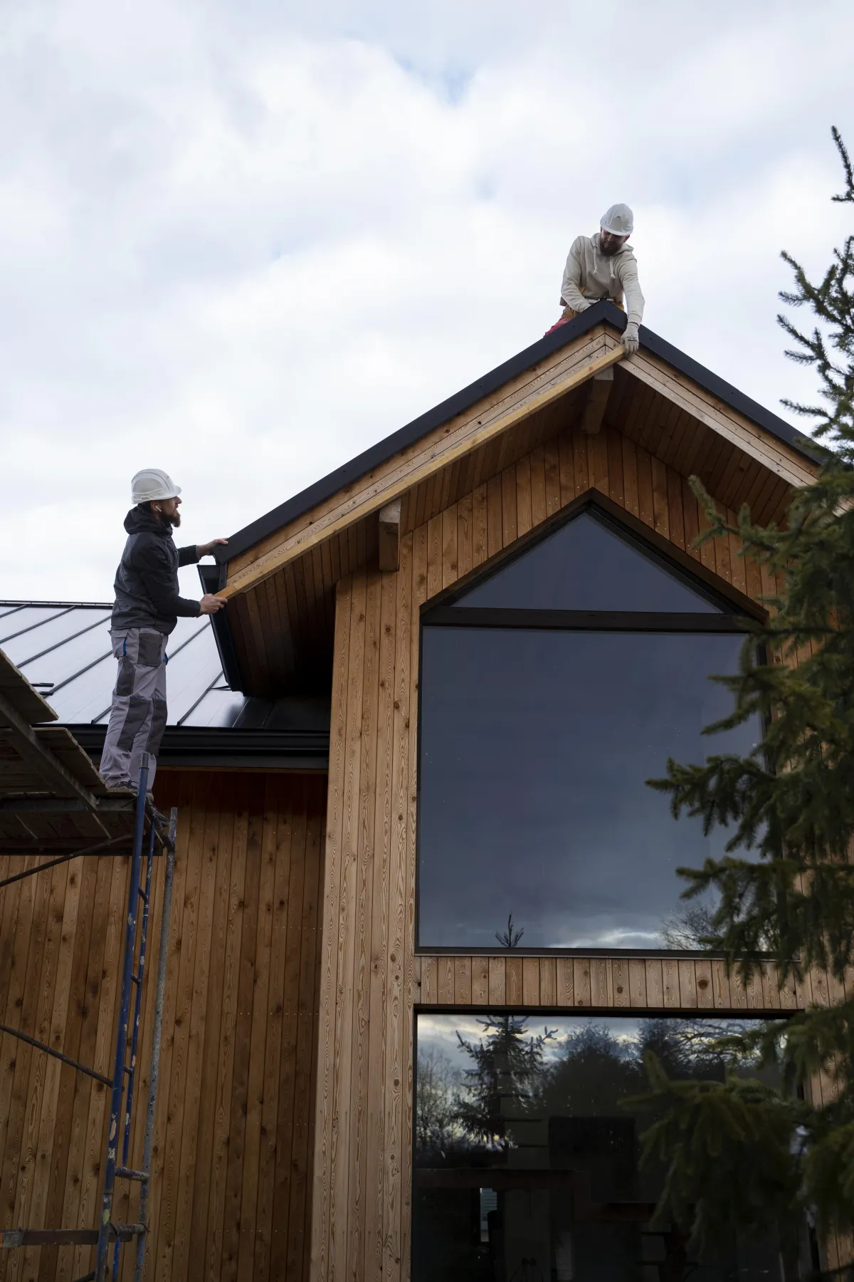 Two roofers working on a residential roof, carefully installing new tiles, demonstrating craftsmanship and teamwork, by JF Roofers.