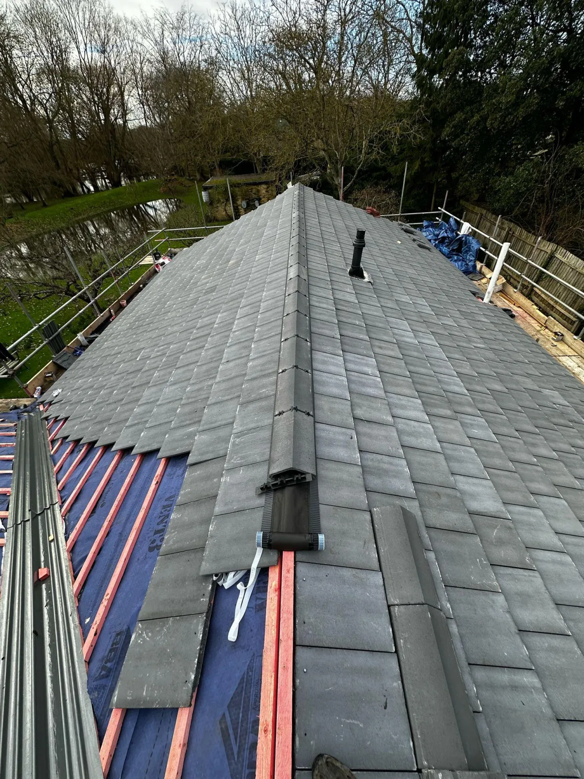 Roofers placing new tiles on the top of a freshly installed roof, ensuring proper alignment and secure installation for long-lasting durability by JF Roofers.