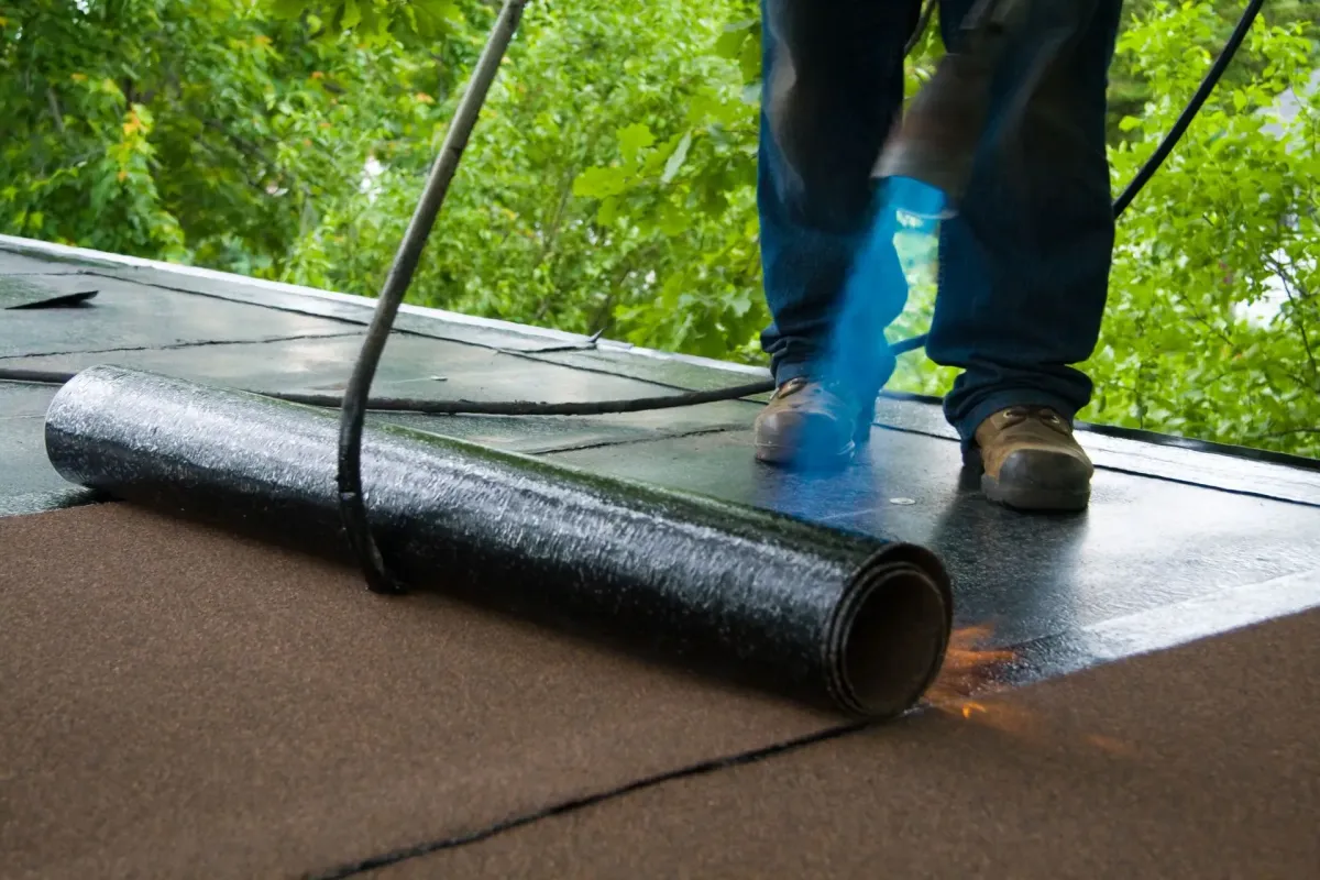 Roofer performing a membrane roof installation, carefully applying the membrane to ensure a waterproof and durable flat roofing solution, by JF Roofers.