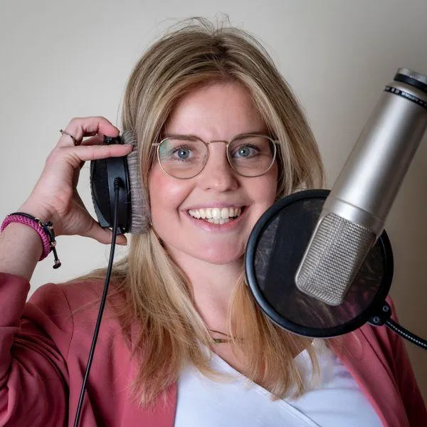 Portret van stemactrice Maartje van Eeden, glimlachend op de bank