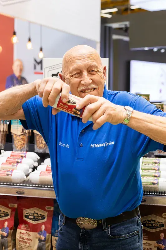 Dr. Jan Pol állatorvos két kézzel tartja a 'Dr. Pol' márkájú lazacos pástétomot promóciós eseményen
