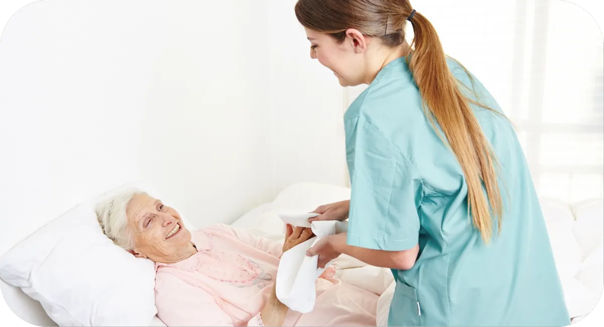 A compassionate caregiver smiling with a happy elderly woman in a wheelchair in a modern home setting.