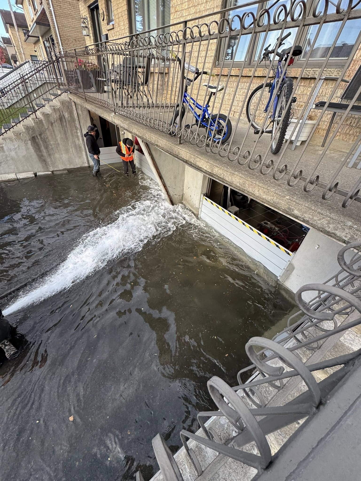 Before: Interior basement with visible water damage—wet floor, scattered belongings, and damp walls; documentary photorealistic shot showing the impact of flooding on a Montérégie home.