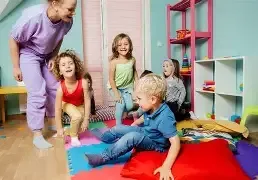 boy sitting on white cloth surrounded by toys