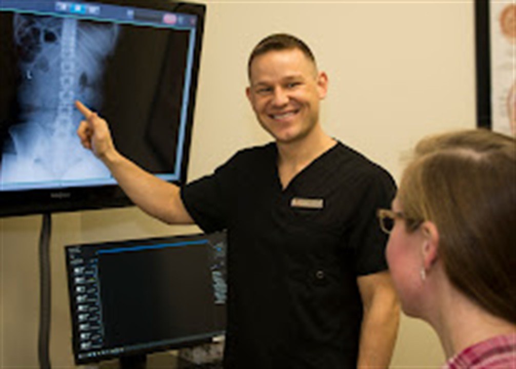 Dr. Justin Luneburg reviewing a patient's spinal x-rays on screen during a consultation