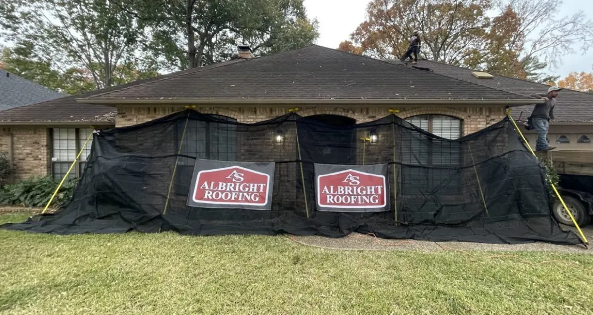 A home with a brand new roof on it. It still has the Catch All tarps up with the Albright roofing logo on them. The Catch All tarps prevent roofing nails and other debris from getting in the customer's flowerbeds, yard and porches.