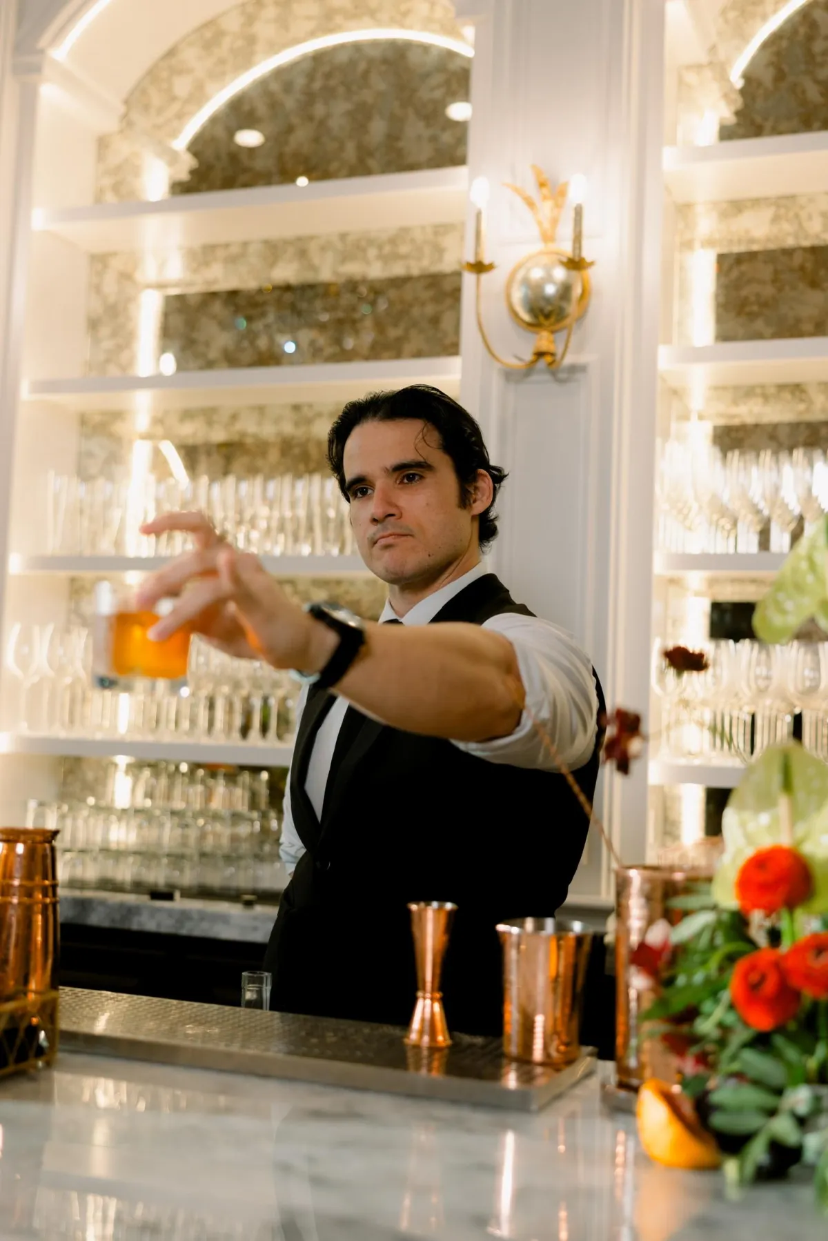 a glass of orange juice next to an orange and a rosemary garnish
