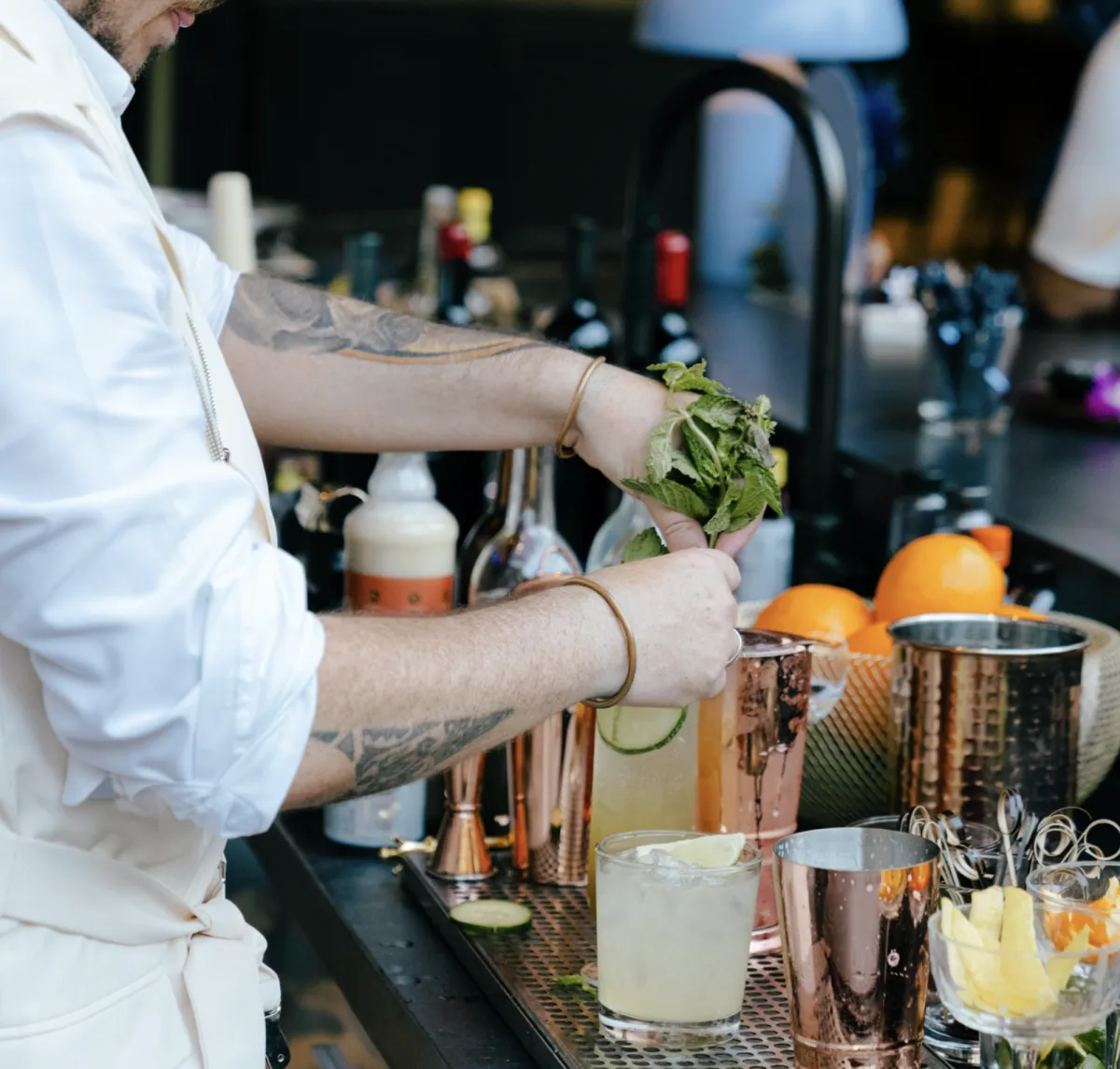 a glass of orange juice next to an orange and a rosemary garnish
