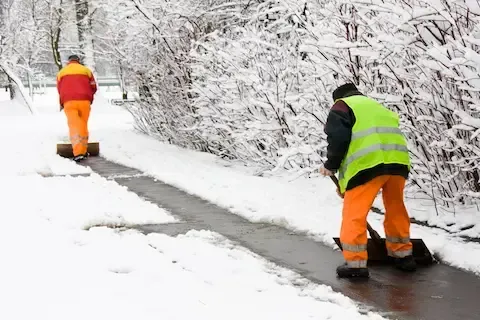 Sidewalk snow removal crew clearing icy path in Davenport