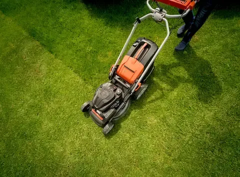 Push mower cutting thick green grass during lawn care service in Sioux City