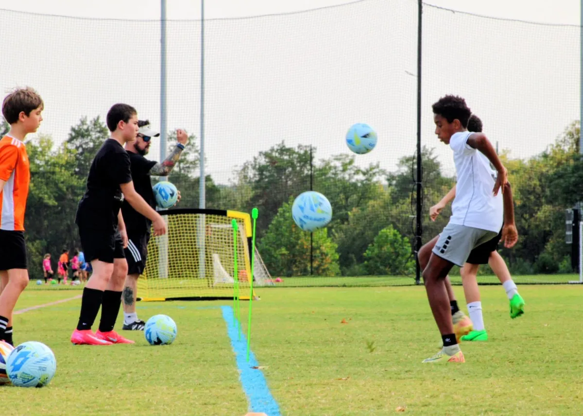 Kids playing soccer with a coach during practice