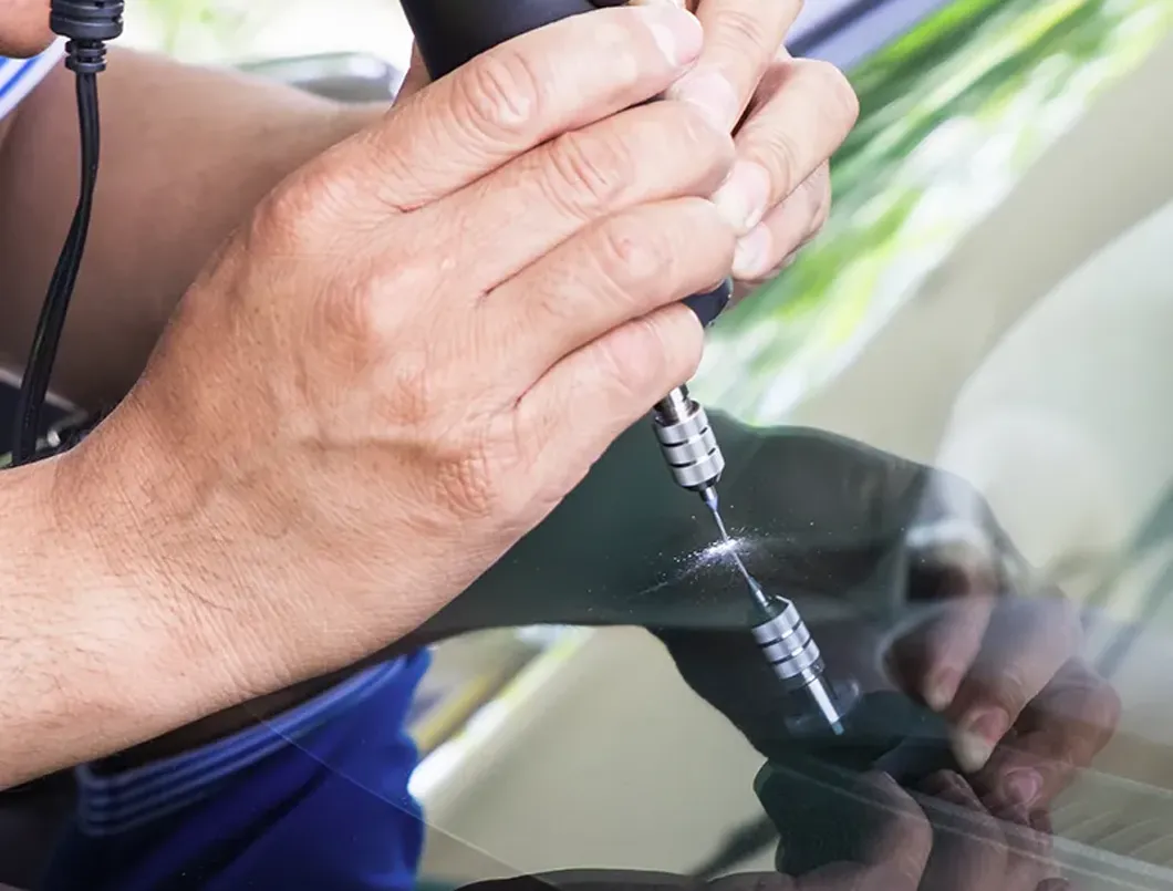 Technician moving a windscreen with suction cups in the workshop