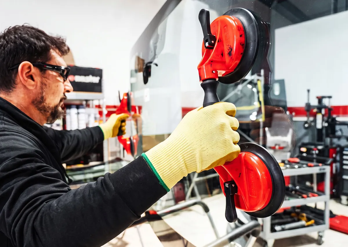 Southern Auto Glass technician using suction cup lifters to handle a windscreen in the Wollongong workshop