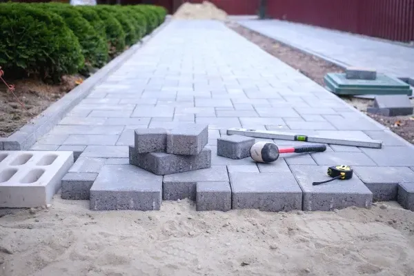Concrete paver walkway under construction with tools and blocks