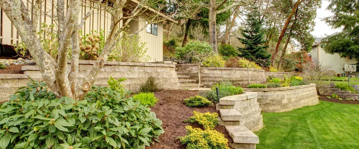 Tiered residential landscaping with decorative retaining walls and lush greenery.