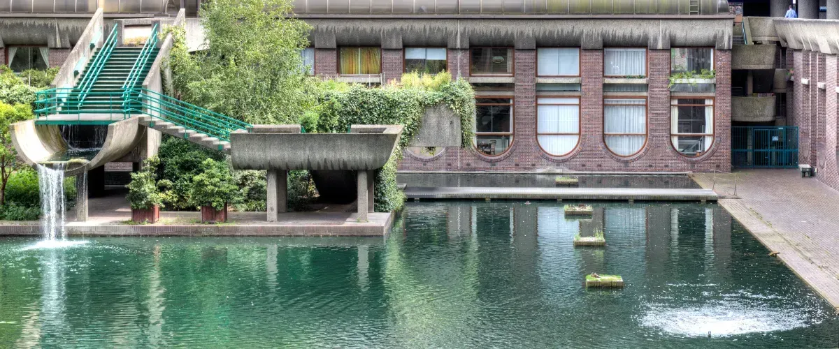 Contemporary urban pond with concrete water feature and landscaping.