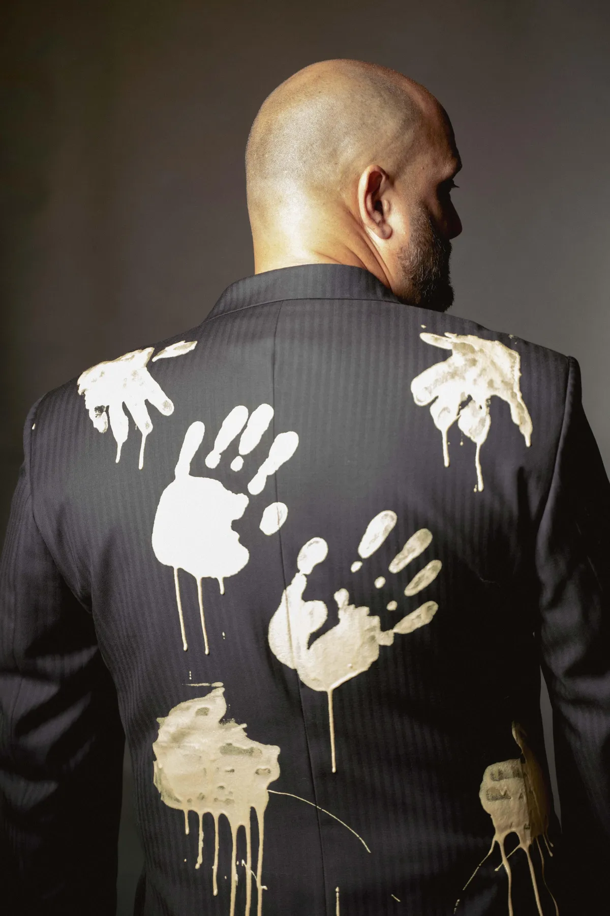 A finished tailored art piece made at the house of suits with painted hand prints on the back of the suit.