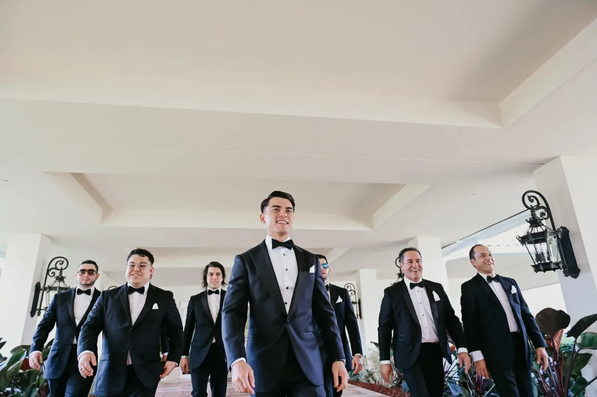 The wedding party is seen walking down the aisle with broad smiles on their faces. The groomsmen are dressed in stylish suits from The House of Suits, featuring classic designs and sleek cuts. With their crisp white shirts, matching ties, and polished shoes, the groomsmen exude elegance and class.