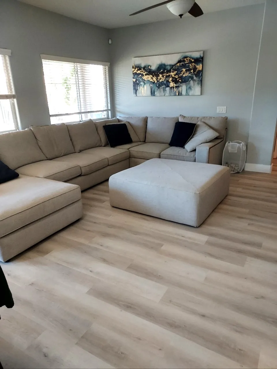 Light colored LVP installed in a living room with family-style couch and ottoman
