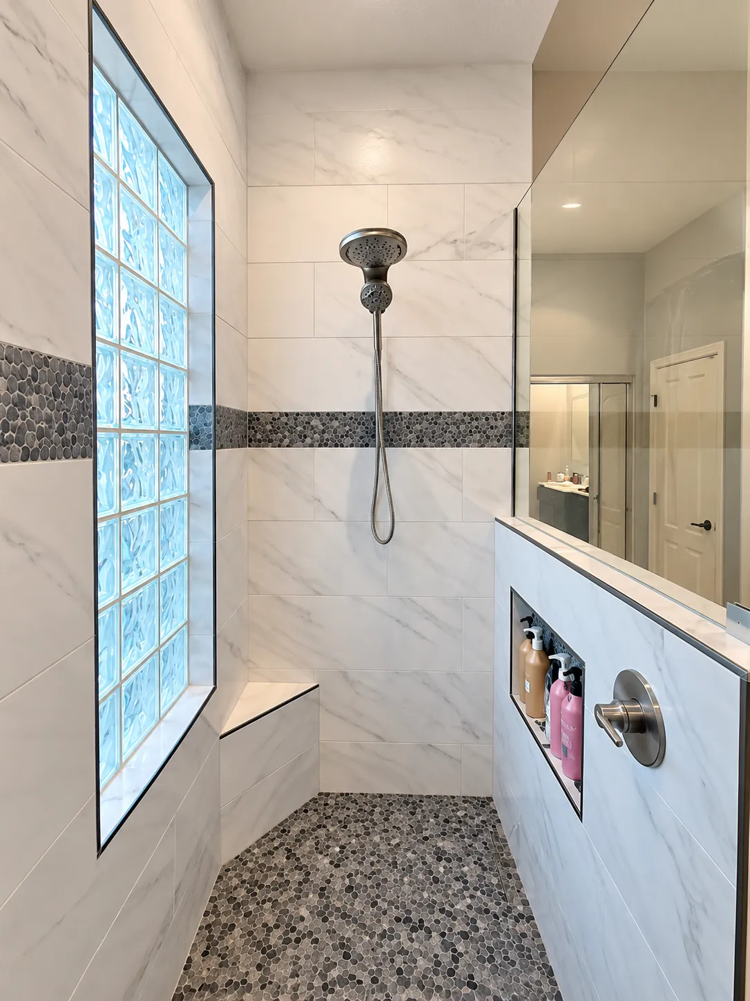 primary shower with marble-like porcelain tile, a corner bench, niche, and pony wall with glass