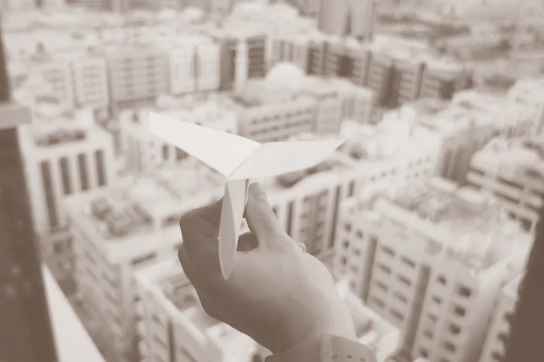 Paper plane launched over a city