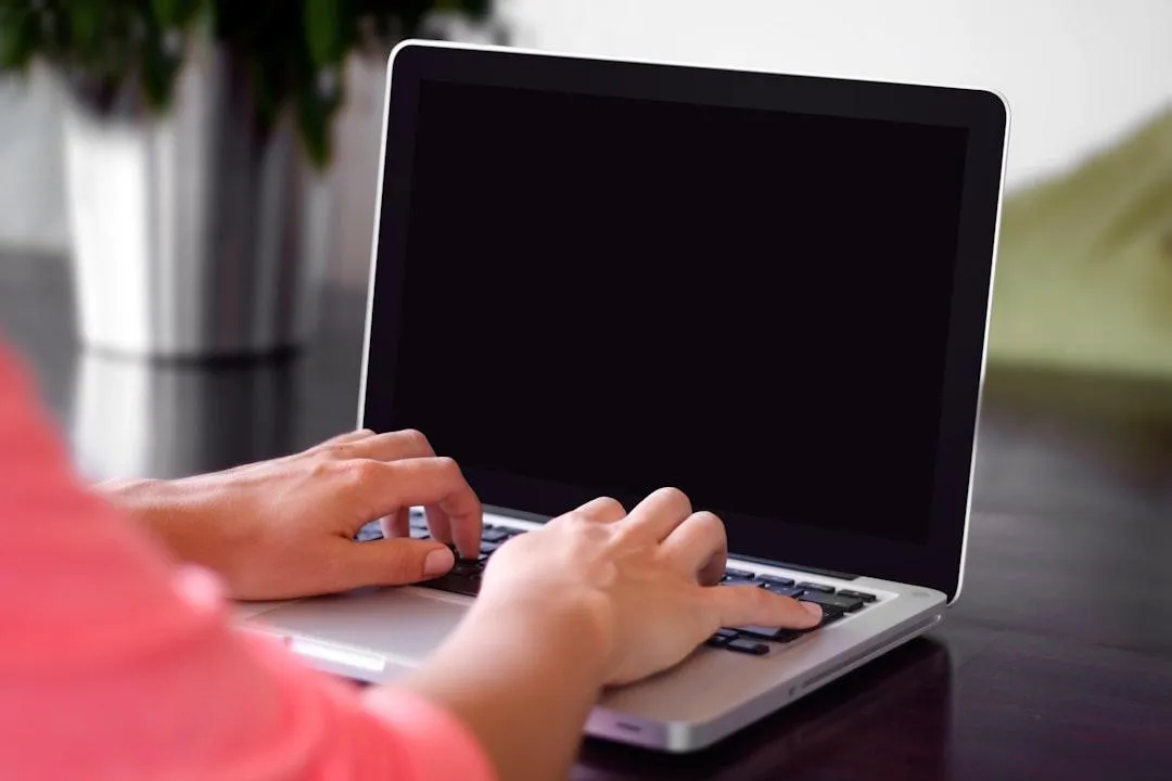 person holding pencil near laptop computer