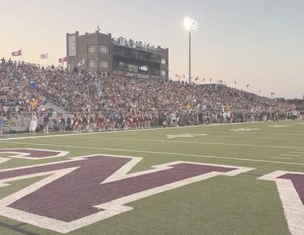 Crowd gathered at the Jenks High School football stadium during an evening game.
