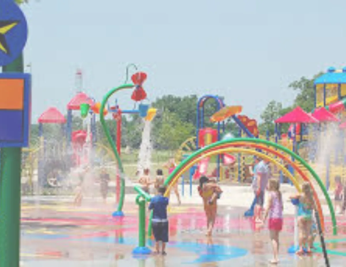 Children playing at the colorful Bixby splash pad and playground during summer.