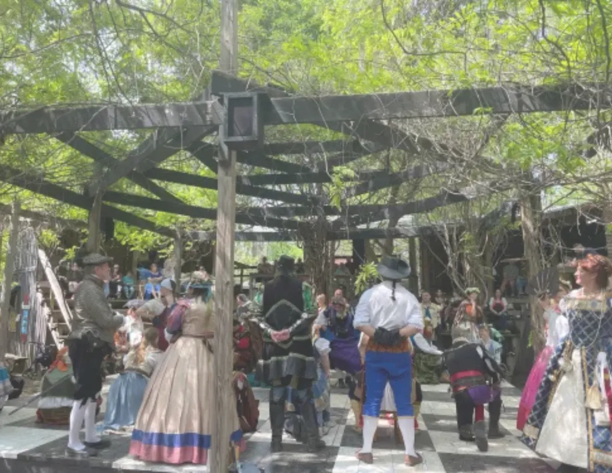 People gathered under shaded pergolas at a local festival of the Renaissance Festival of Musogee