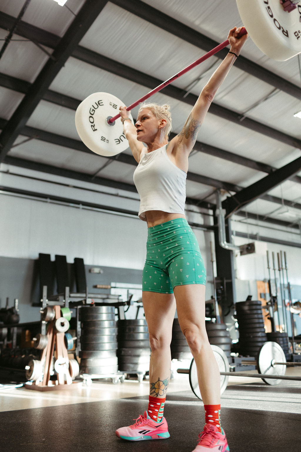 Woman performing pull-ups in the gym with 'humble, healthy, happy' painted on the wall behind her