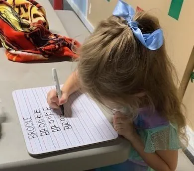 Girl stretches to the side while watching teacher on large screen TV