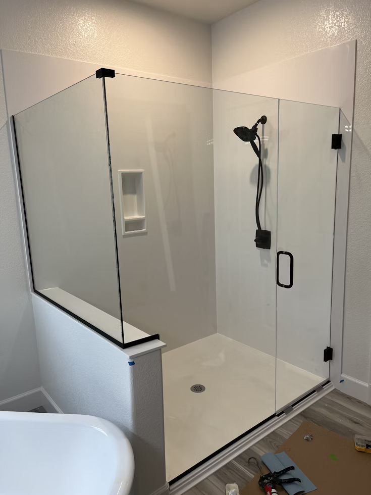 frameless shower enclosure with black shower head and faucet
