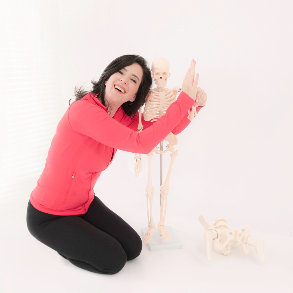 Tracy Seider playfully demonstrating whole-body skeletal alignment with an anatomical skeleton model