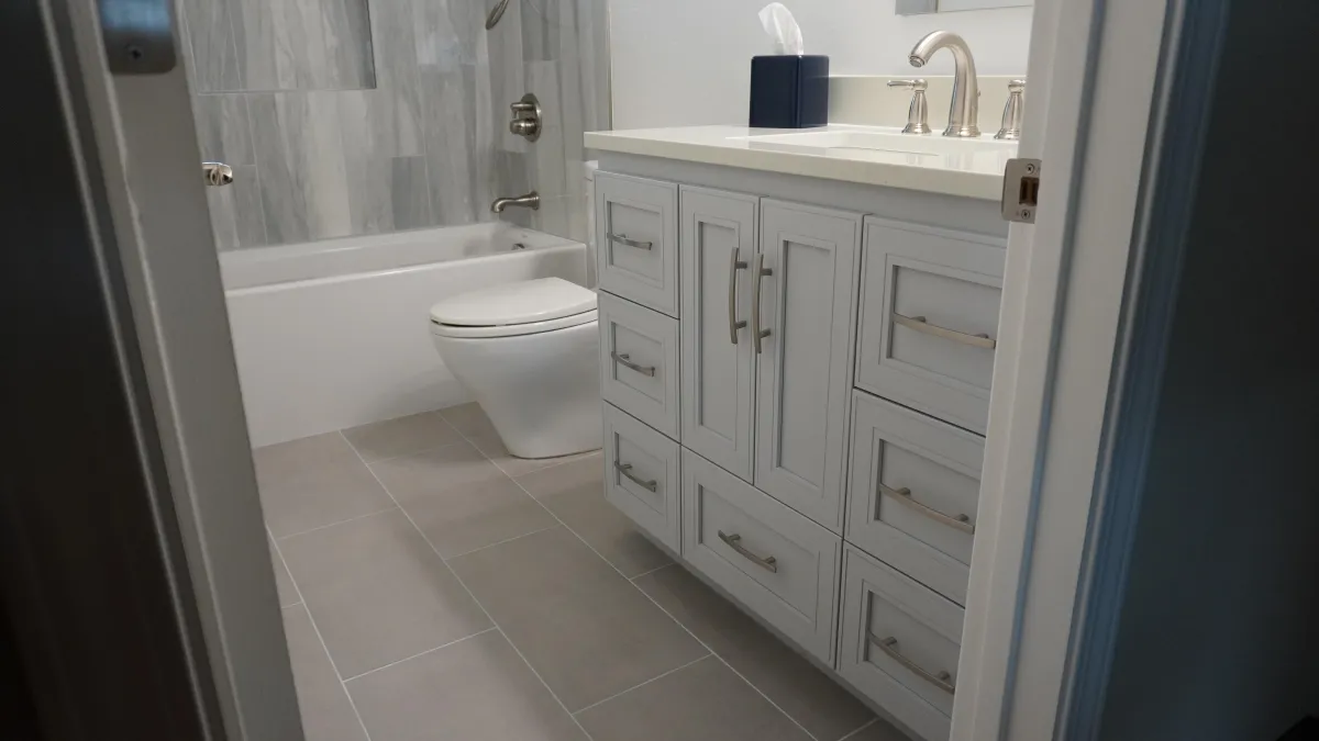 Bathroom remodel featuring a iight blue vanity, stainless steel faucet, white tube, light grey floor tile in Petaluma, CA.